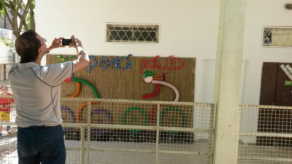 בעלי היקר מצלם מהחצר את הפיסול המורכב על קיר המעבדה