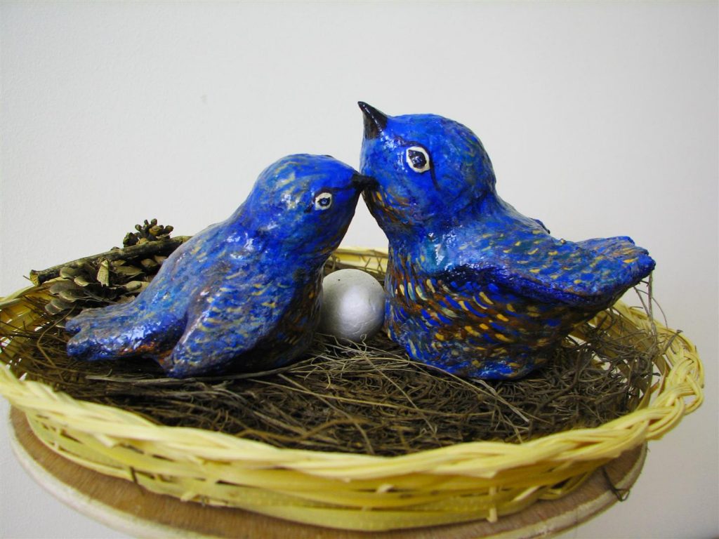 זוג ציפורים אוהבים עם פרי אהבתם בקן האהבה