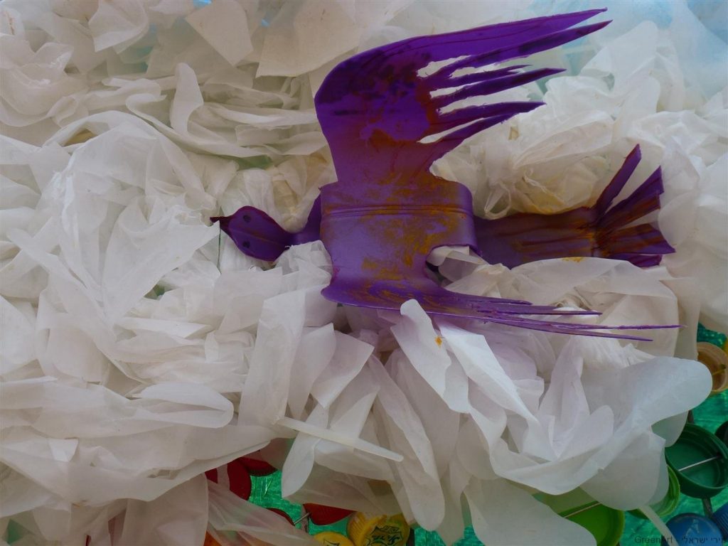 ציפור במעופה מבקבוק פלסטיק סגול על ענן משקיות ניילוןלבנות