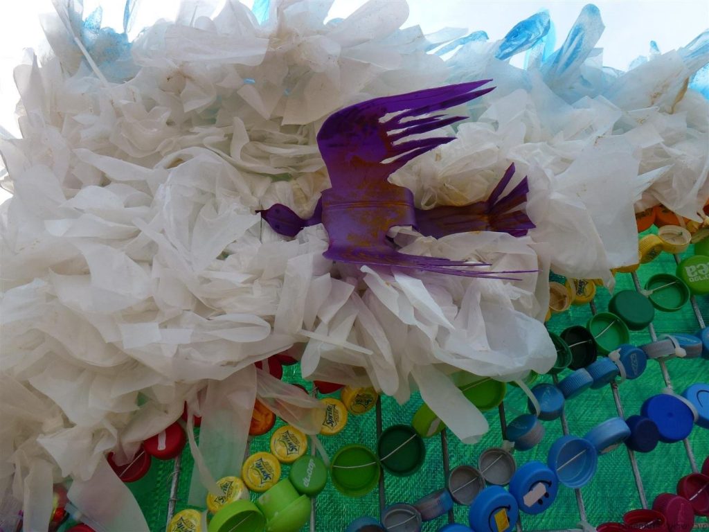 ציפור במעופה מבקבוק פלסטיק סגול על ענן משקיות ניילון