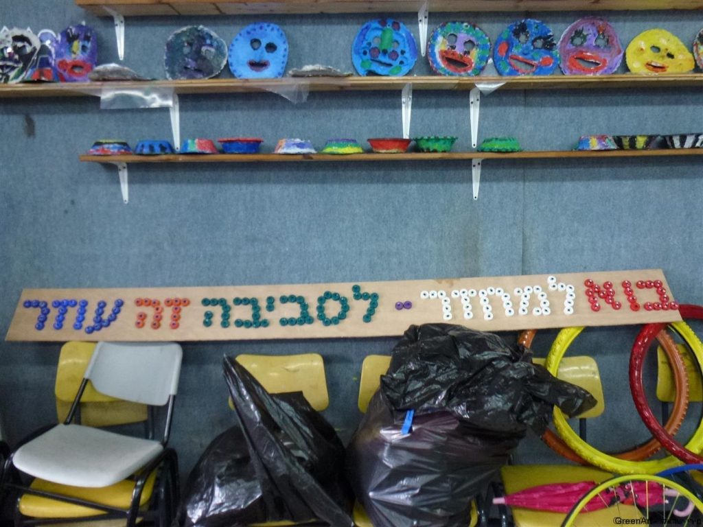 השלט שיצרנו על קרש עץ ישן והכיתוב מפקקי פלסטיק בשימוש חוזר