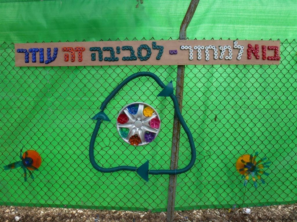סמל המיחזור מחומרים ממוחזרים ושלט המזמין את הקהילה למחזר