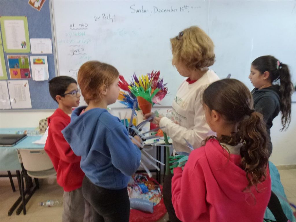 דפנה מדריכה את התלמידים כיצד לעצב פרחים מבקבוקים שונים