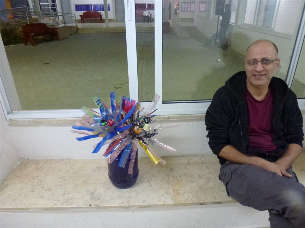אב יצירתי גאה בפרי יצירתו פרחים מעוצבים שמעצבים אגרטל מבקבוק פלסטיק כחול