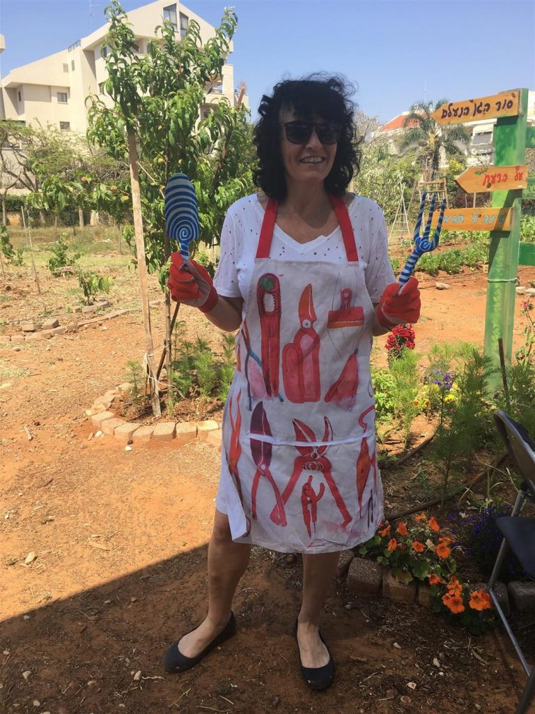 עליזה עם סינר חקלאי וכלי עבודה שתרמה לגינה - מאי 2017