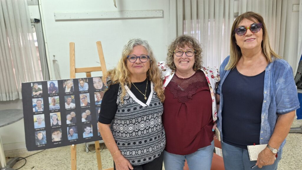 עם ודי ויפה מלול מנתיב העשרה - שמאחוריה שלט עם 20 הנרצחים מהישוב נתיב העשרה