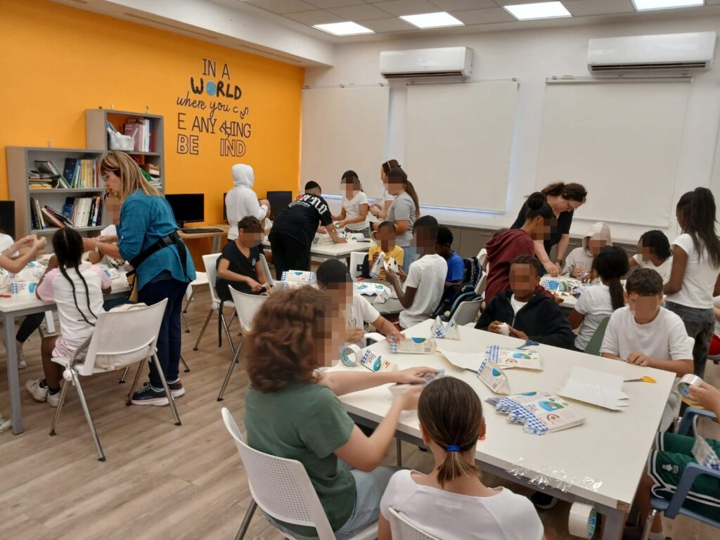 תלמידי שכבת כיתות ו' לומדים בסדנת היצירה לעצב שרפרפים מקרטוני חלב לפינת ישיבה ידידותית לסביבה